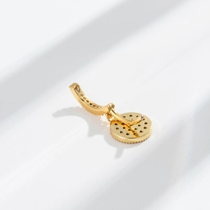 Macro shot of gold-plated navel ring with crystal inlay on a minimalist white background