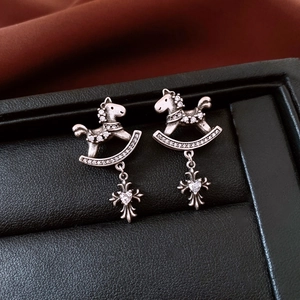 Detail of vintage silver horse earrings with sparkling zircons and a cross pendant