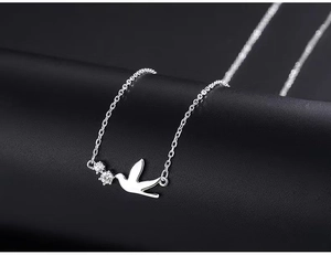 Macro shot of silver bird pendant necklace with two sparkling cubic zirconia stones