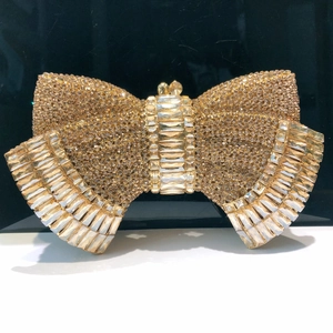 Close-up of champagne gold bow-shaped clutch bag with sparkling encrusted rhinestones