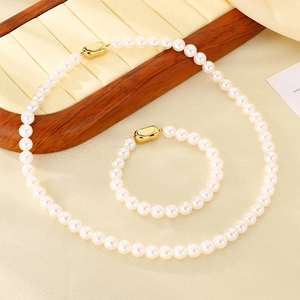 Gros plan d'un ensemble collier et bracelet en perles blanches avec fermoir doré
