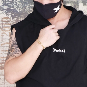 Gros plan d'un bracelet punk en acier doré avec des maillons en spirale au poignet