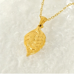 Vue macro du pendentif feuille en or 18k avec textures de pièces sur marbre blanc