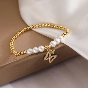 Detailed view of a gold beaded bracelet with pearls and a sparkling butterfly charm