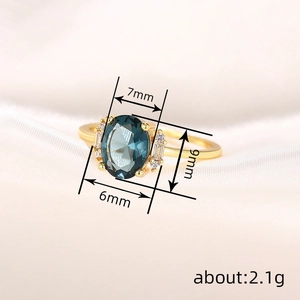 Elegant gold oval blue gemstone ring with accent diamonds on white silk background