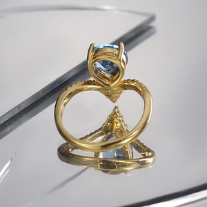 Macro detail of a pear-shaped blue zircon ring with a V-shaped golden band and tiny diamonds
