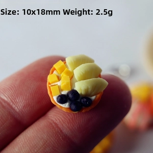 Macro shot of 10x18mm dollhouse fruit tart miniature held on a fingertip for scale