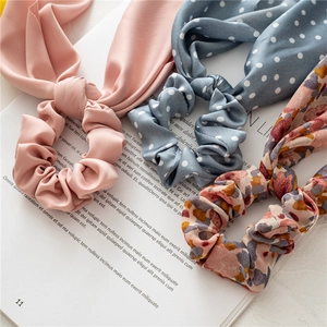 Close-up of floral, polka dot, and solid pink long ribbon scrunchies on a magazine