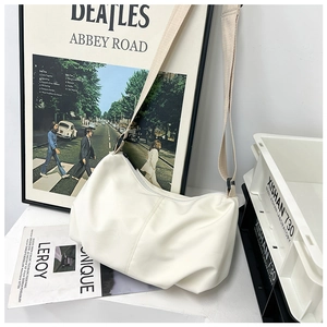 Detail of a creamy white pleated dumpling bag featuring a wide canvas strap and PU texture