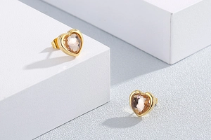 Close-up of champagne heart-shaped crystal earrings on white geometric background