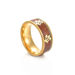 Detail of gold titanium ring with wood inlay and engraved sea turtle patterns