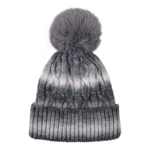 Detailed view of cable knit pattern and large pom-pom on grey gradient winter hat
