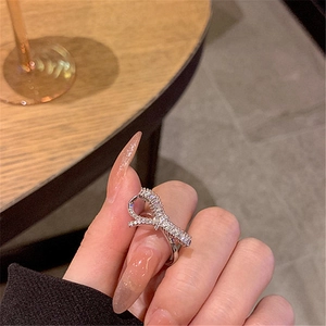 Detail shot of a silver bow ring set with sparkling stones on a model's hand