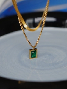 Detailed macro shot of vintage double-layer gold chain with rectangular emerald zircon