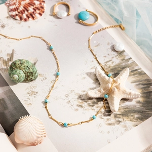 Mise à plat de collier et bagues en turquoise dorée avec coquillages pour l'été