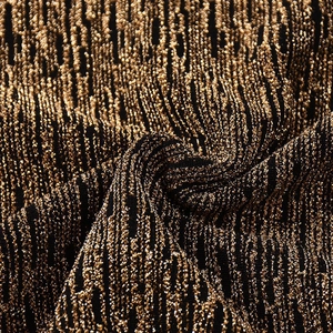Détail macro du tissu en maille lurex métallique avec des reflets dorés