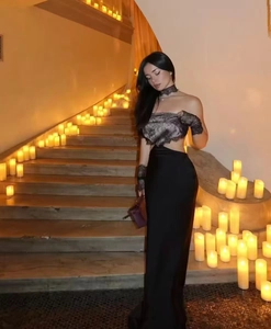 Close-up of elegant black satin evening dress with intricate lace stitching on stone steps