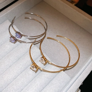 Détail de boucles d'oreilles en C dorées et argentées avec cristaux de zircon sur boîte