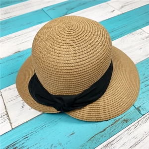 Dettaglio cappello di paglia intrecciato con fiocco nero su legno a righe blu