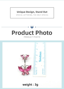 Macro detail of silver navel ring featuring dual pink butterfly rhinestones and curved bar