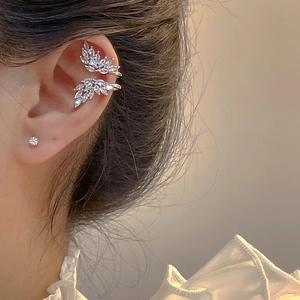 Élégant ear cuff plume argentée avec pierres de zircone porté sur l'oreille du modèle