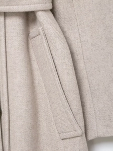 Dettaglio del cappotto di lana color avena con cintura a doppio petto e cuciture