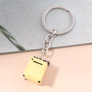 Macro shot of a yellow suitcase keychain charm with metal ring and black luggage details