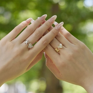 Detail of adjustable silver and gold rings with cross and heart designs on hands
