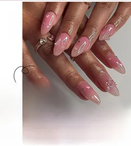 Detail of pink gradient almond nails with crystal rhinestones and 3D bow decorations