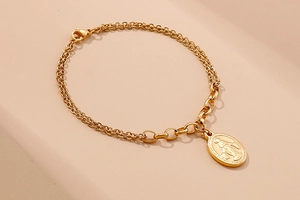Detail of gold coin bracelet with Virgin Mary pendant and mixed chain link design