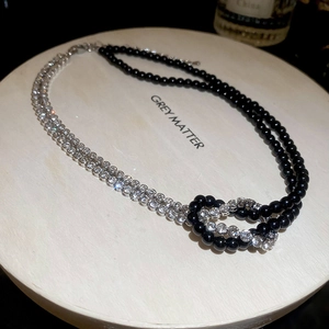 Dettaglio della collana Y2K con perle nere, cristalli e un design a doppio strato con nodo