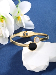 Macro shot of gold-plated geometric bangle featuring white and black inlaid elements