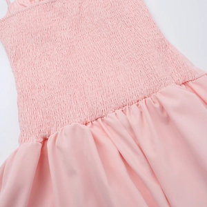 Vue détaillée du tissu smocké élastique rose et de l'ourlet à volants de la robe d'été