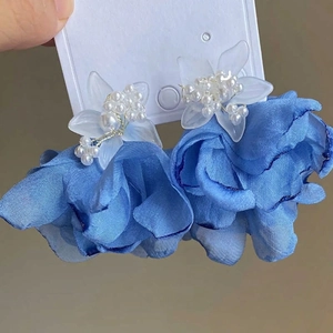 Detailed close-up of blue silk flower earrings with pearl accents and floral centers