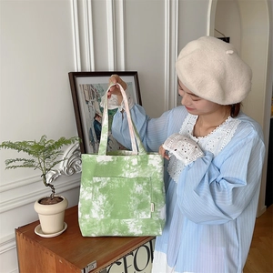 Dettaglio della borsa tote in tela tie-dye verde con tasca frontale in stile minimal