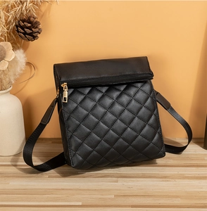 Détail d'un sac bandoulière noir matelassé en cuir synthétique avec fermeture éclair dorée