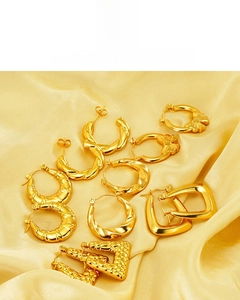 Flat lay of 18K gold plated twisted bow and geometric earrings on yellow silk fabric