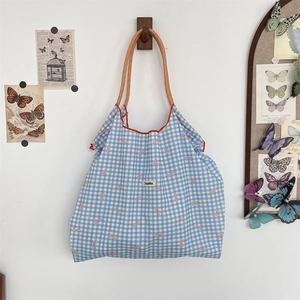 Detail of blue plaid tote bag with pink bow patterns and braided rope handles