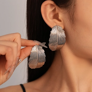 Chunky silver leaf earrings with textured veins showing model wear and size
