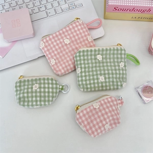 Detail of floral embroidery on pink and green plaid cosmetic pouch with gold zipper