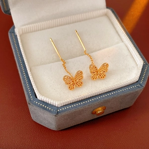 Close-up of gold butterfly threader earrings in a velvet gift box showing hollow wings