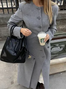 Detail of grey wool coat with large round buttons and black leather handbag accessory