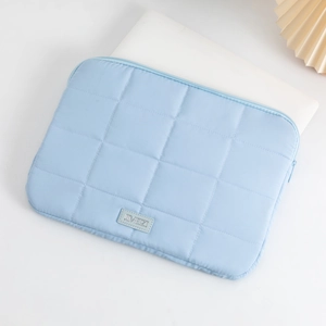 Close-up of a light blue quilted laptop sleeve with a minimalist puffed texture design
