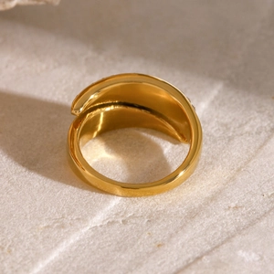 Polished gold stainless steel open ring displayed on a natural stone surface
