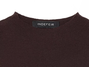 Detailed view of the round neckline and woven brand label on dark brown knit top