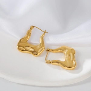 Gros plan de boucles d'oreilles croissant dorées sur fond de tissu en soie blanche