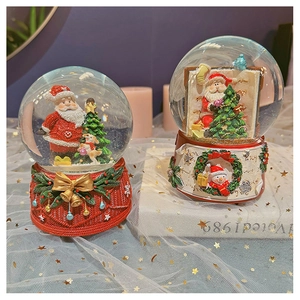 Detail of Christmas snow globe with Santa and reindeer on textured resin base