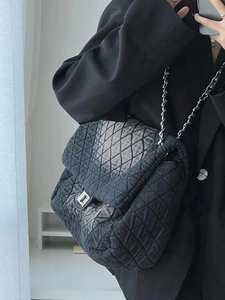 Close-up of quilted denim shoulder bag with silver chain strap and metal clasp detail