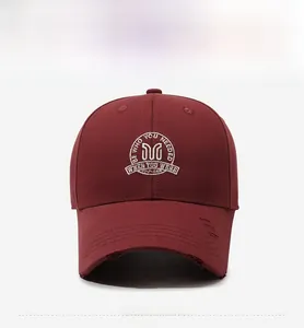 Detail of embroidered white M letter and vintage distressed brim on burgundy baseball cap