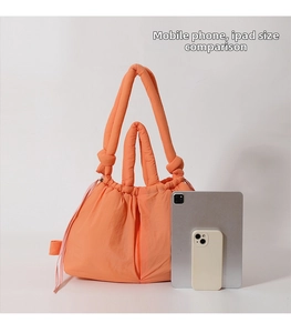 Size comparison of orange padded tote bag with tablet and phone for scale reference